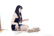 Sitting on bed long hair holding rope